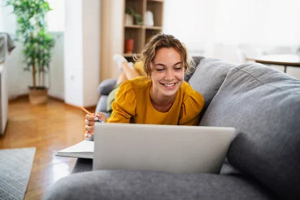 Young woman using laptop while relaxing on a comfortable sofa